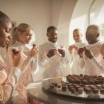a group of people in iridescent future outfits savor exquisite geometrically perfect chocolates